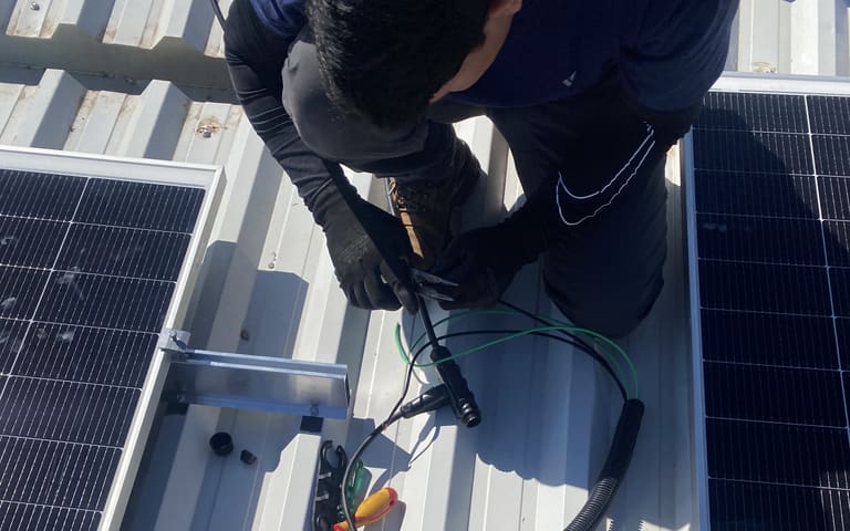 Técnico realizando a manutenção de painéis solares em telhado
